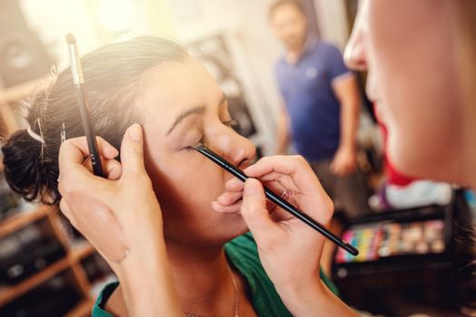 Close-up of a makeup artist getting eyeshadow to model.