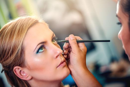 Make-up artist applying the eyeshadow to model. Close-up. 