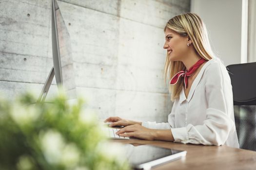 Young beautiful successful female entrepreneur working on computer at the office.