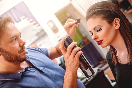 Man hairdresser making hairstyle of a customer woman.  