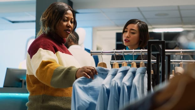 Female customer shopping for formal or casual wear, checking new fashion shop merchandise. Young adult checking boutique clothes in department store, small business. Handheld shot.