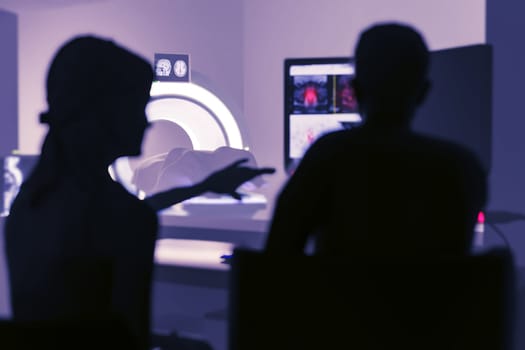 In Control Room Doctor and Radiologist Discuss Diagnosis while Watching Procedure and Monitors Showing Brain Scans Results, In the Background Patient Undergoes MRI or CT Scan Procedure.3D rendering .