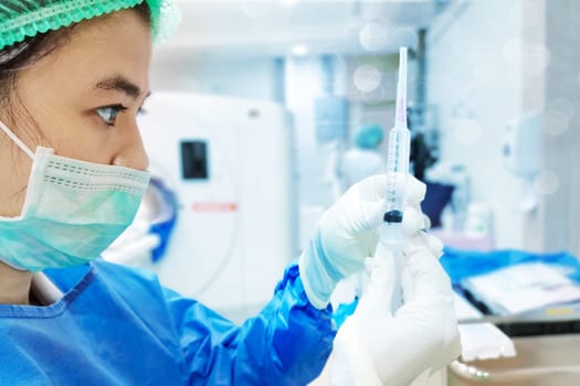 Woman Doctor with Safety PPE gown protective workwear holding Vaccine and syringe on CT Scan room background. Female doctor with face mask gloves in Hospital, preparing vaccine.