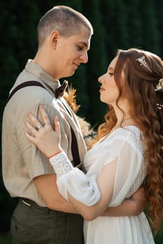 wedding walk of the bride and groom in a coniferous park in summer