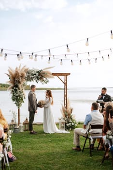 wedding ceremony of the newlyweds in a country cottage on a green hill