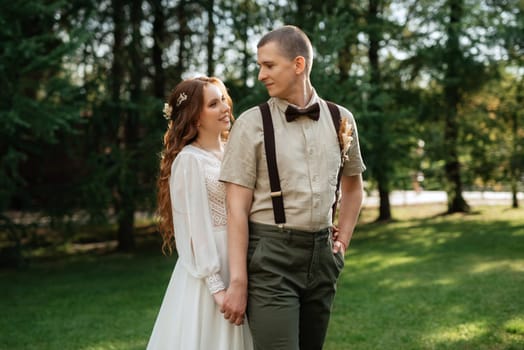 wedding walk of the bride and groom in a coniferous park in summer