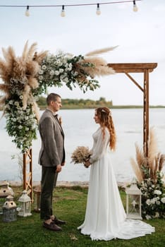 wedding ceremony of the newlyweds in a country cottage on a green hill