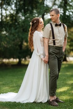 wedding walk of the bride and groom in a coniferous park in summer