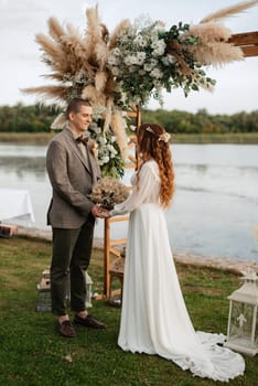 wedding ceremony of the newlyweds in a country cottage on a green hill