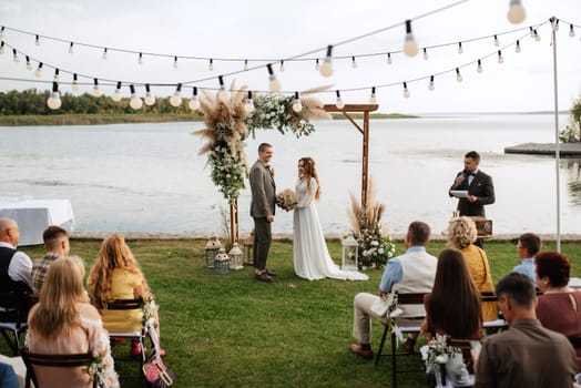 wedding ceremony of the newlyweds in a country cottage on a green hill