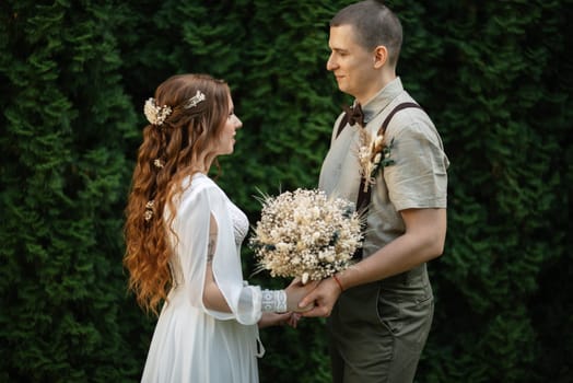 wedding walk of the bride and groom in a coniferous park in summer