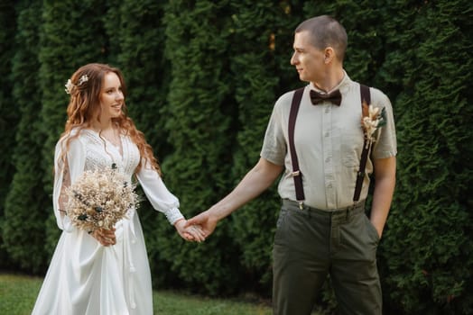 wedding walk of the bride and groom in a coniferous park in summer