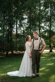 wedding walk of the bride and groom in a coniferous park in summer