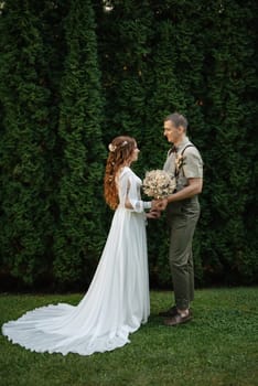 wedding walk of the bride and groom in a coniferous park in summer