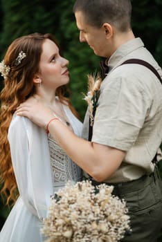 wedding walk of the bride and groom in a coniferous park in summer