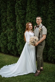 wedding walk of the bride and groom in a coniferous park in summer