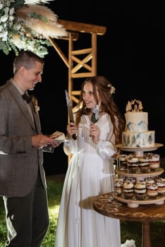 newlyweds happily cut, laugh and taste the wedding cake