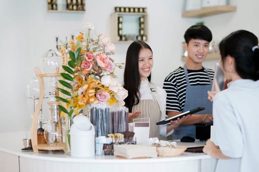 Asia Barista waiter take order from customer in coffee shop, cafe owner writing drink order at counter bar. Service mind concept. Point of Sale System, Take-out Foods, and Small Business Concepts.