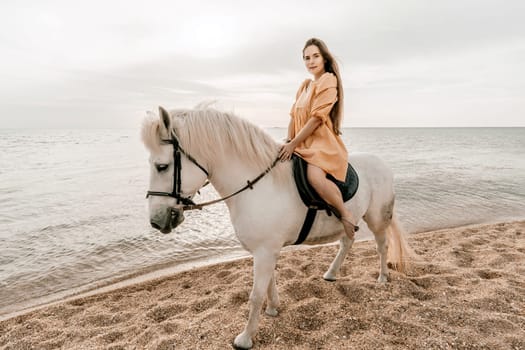 A white horse and a woman in a dress stand on a beach, with the sky and sea creating a picturesque backdrop for the scene