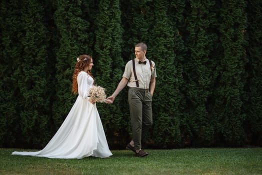 wedding walk of the bride and groom in a coniferous park in summer