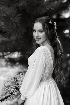 red-haired girl bride with a wedding bouquet on a meadow with green thuja