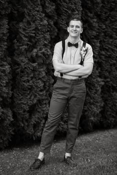 young guy the groom in the image in the style of boho on the background of green thuja