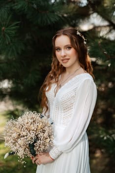 red-haired girl bride with a wedding bouquet on a meadow with green thuja