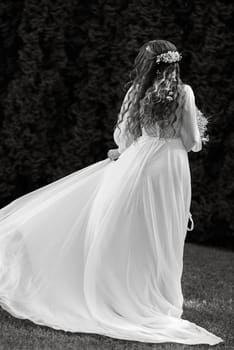 red-haired girl bride with a wedding bouquet on a meadow with green thuja