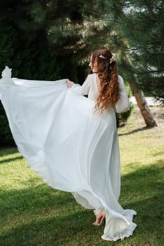 red-haired girl bride with a wedding bouquet on a meadow with green thuja