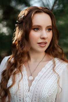 red-haired girl bride with a wedding bouquet on a meadow with green thuja