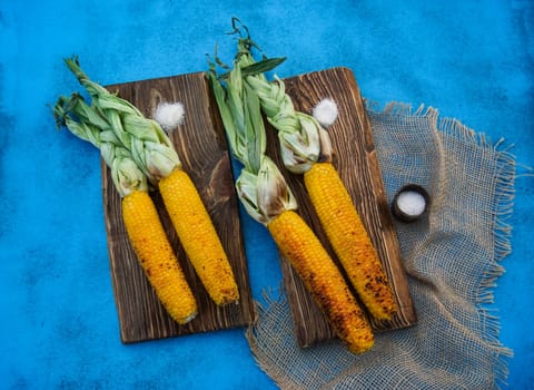 On the blue table is grilled ripe yellow corn. High quality photo