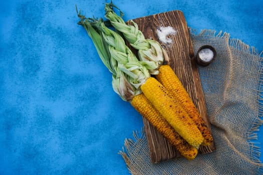 On the blue table is grilled ripe yellow corn. High quality photo