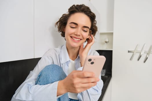 Portrait of woman sitting at home with mobile phone, online shopping on smartphone app, spending time indoors.