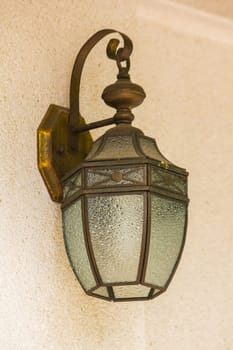 The old glass lantern was attached to the white wall.