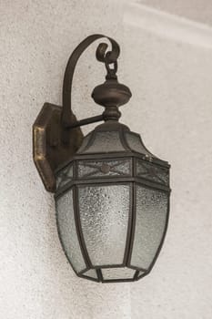 The old glass lantern was attached to the white wall.