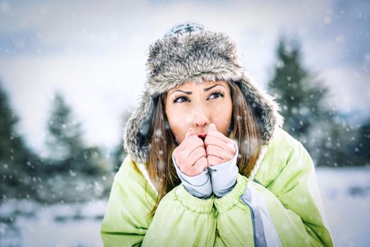 Beautiful young frozen woman skier in winter vacations, standing and looking away.