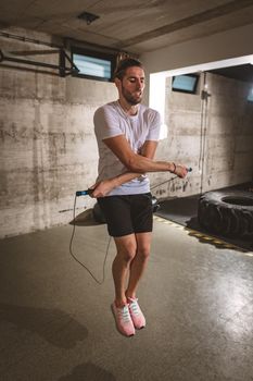 Young man exercising using skipping rope in gym. 