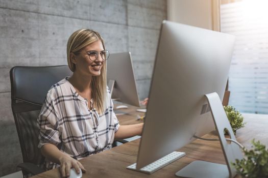 Young beautiful successful smiling business woman working on computer in the office.