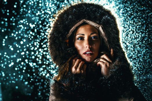 Beautiful young scared woman in winter jacket with fur hood worries and is looking away waiting for somebody.