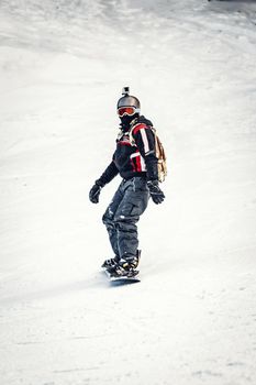 Young man rides snowboard and enjoying a frozen winter day on mountain slopes.