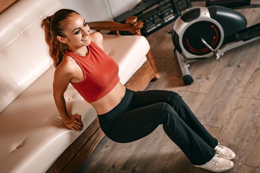 Beautiful young woman doing stretching exercises at home.