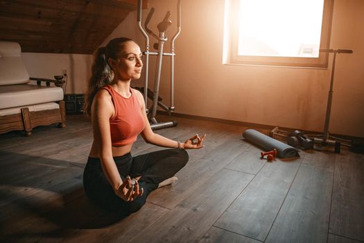 Beautiful young woman doing yoga at her living room.