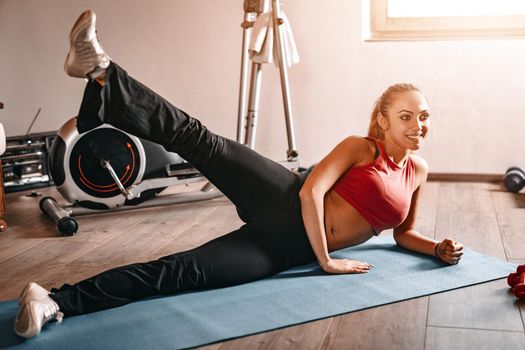 Beautiful young woman doing exercises at her living room.