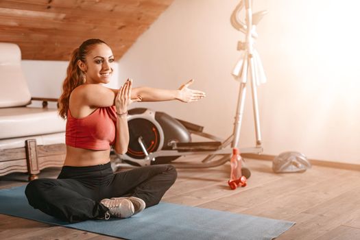 Beautiful young woman doing stretching exercises at home.