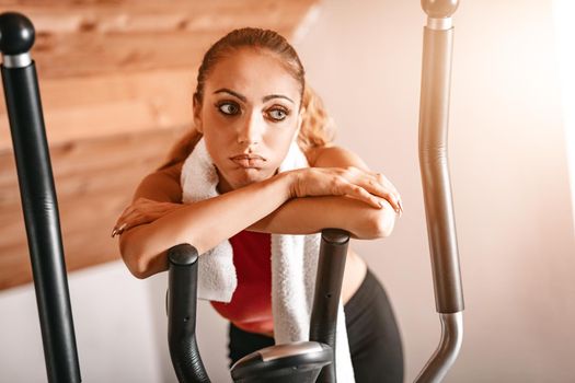 Attractive woman is exhausted and taking a break from hard exercising in living room at home.