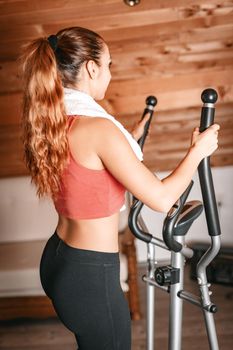 Beautiful young woman exercising on stepper at home.