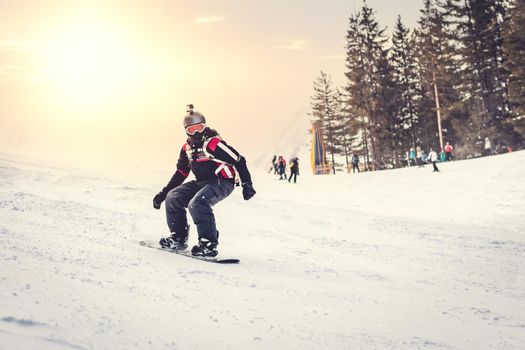 Young man rides snowboard and enjoying a frozen winter day on mountain slopes.