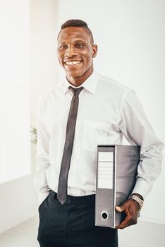 Successful African businessman is holding a folder in modern office and planning what to do next.