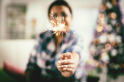 Cheerful woman is having fun with sparkle in the apartment in casual clothes.