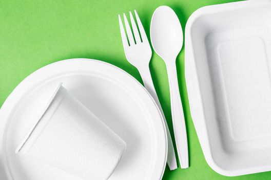 Eco friendly biodegradable paper disposable for packaging food and paper glass on green background.